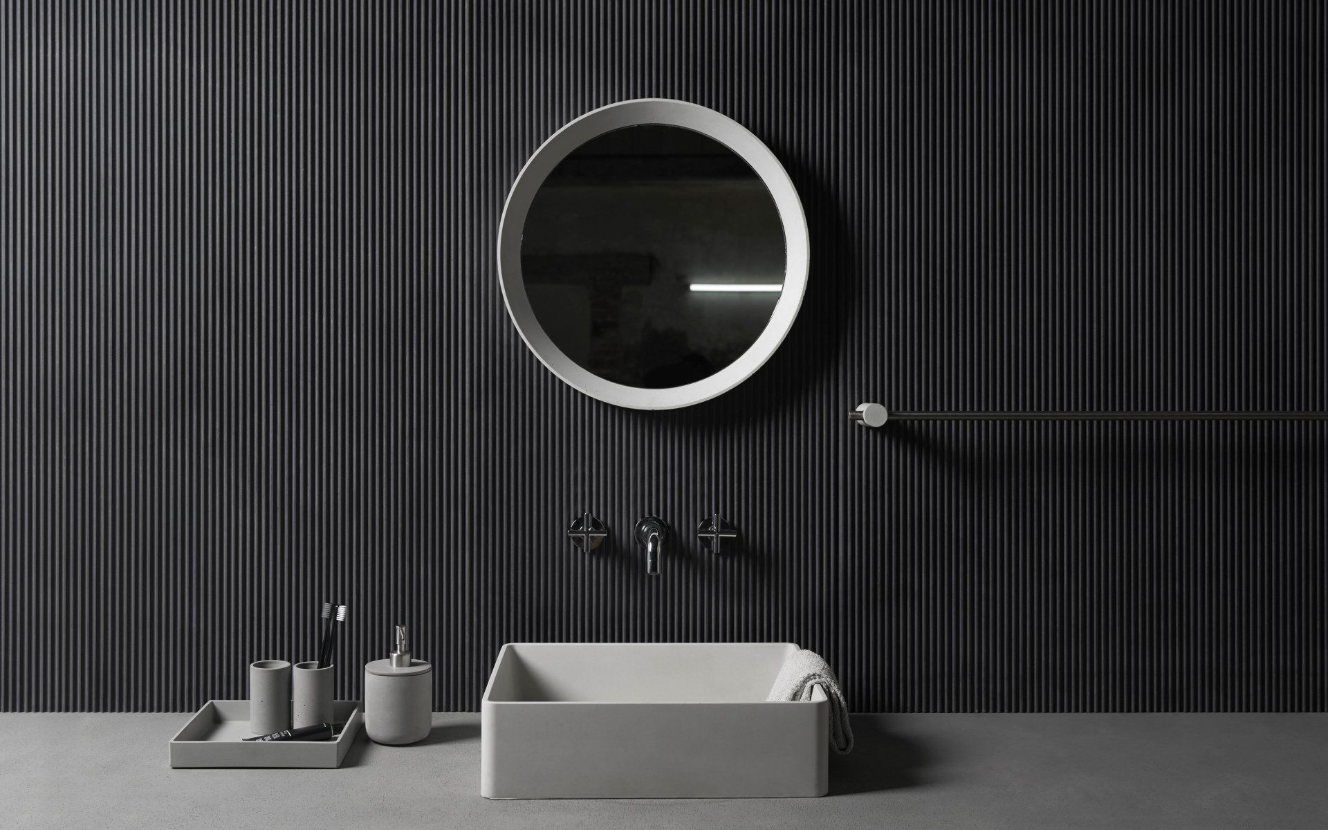 réhabilitation d'architecte d'une salle de bain avec mur et robinetterie noirs munie d'un vasque à poser carré en céramique et miroir rond à bord blancs