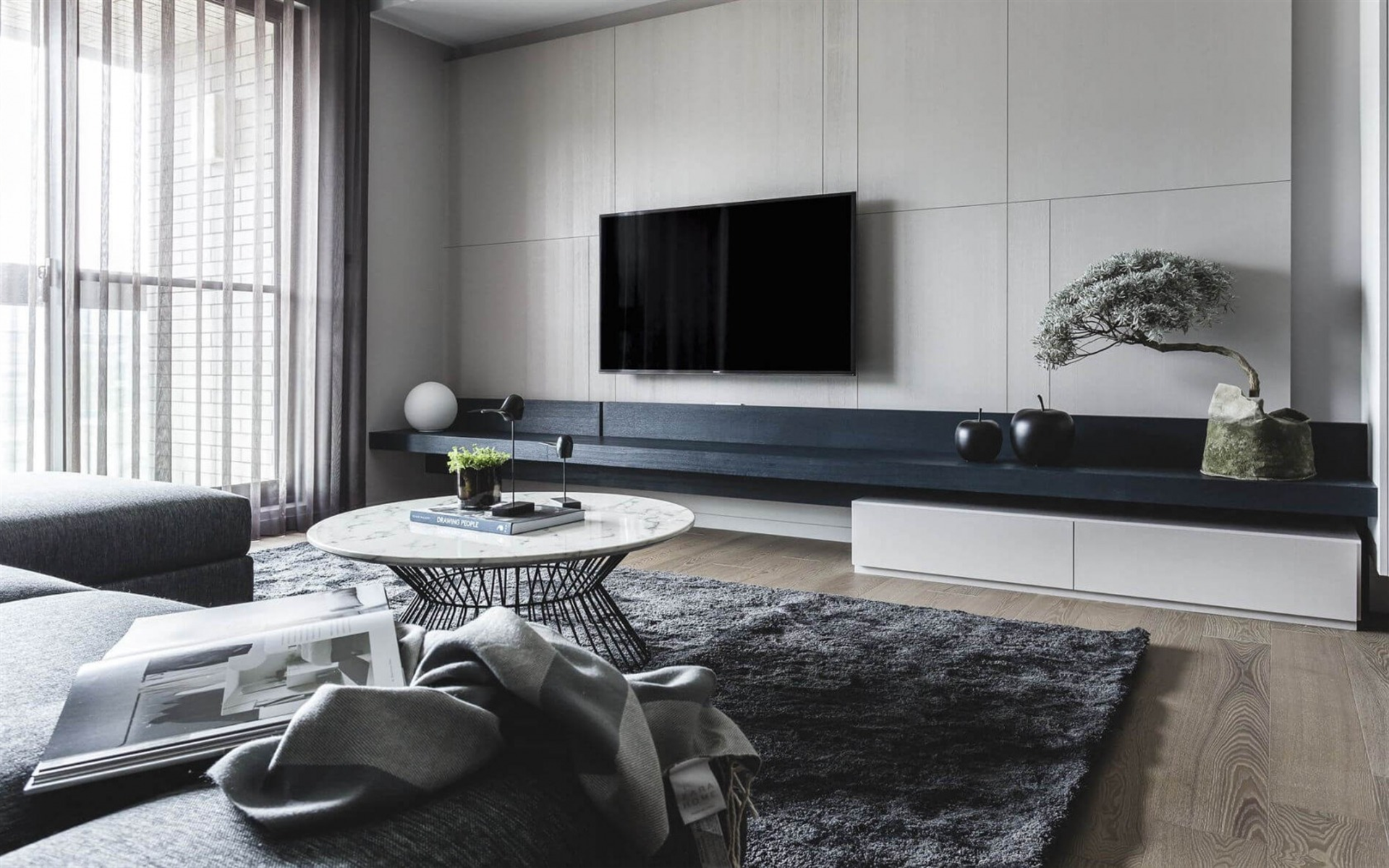 rénovation d'architecte d'un salon doté d'un parquet en chêne moyen, canapé d'angle et tapis gris, table basse métal noir avec plateau en marbre blanc donnant sur un banc TV en bois noir