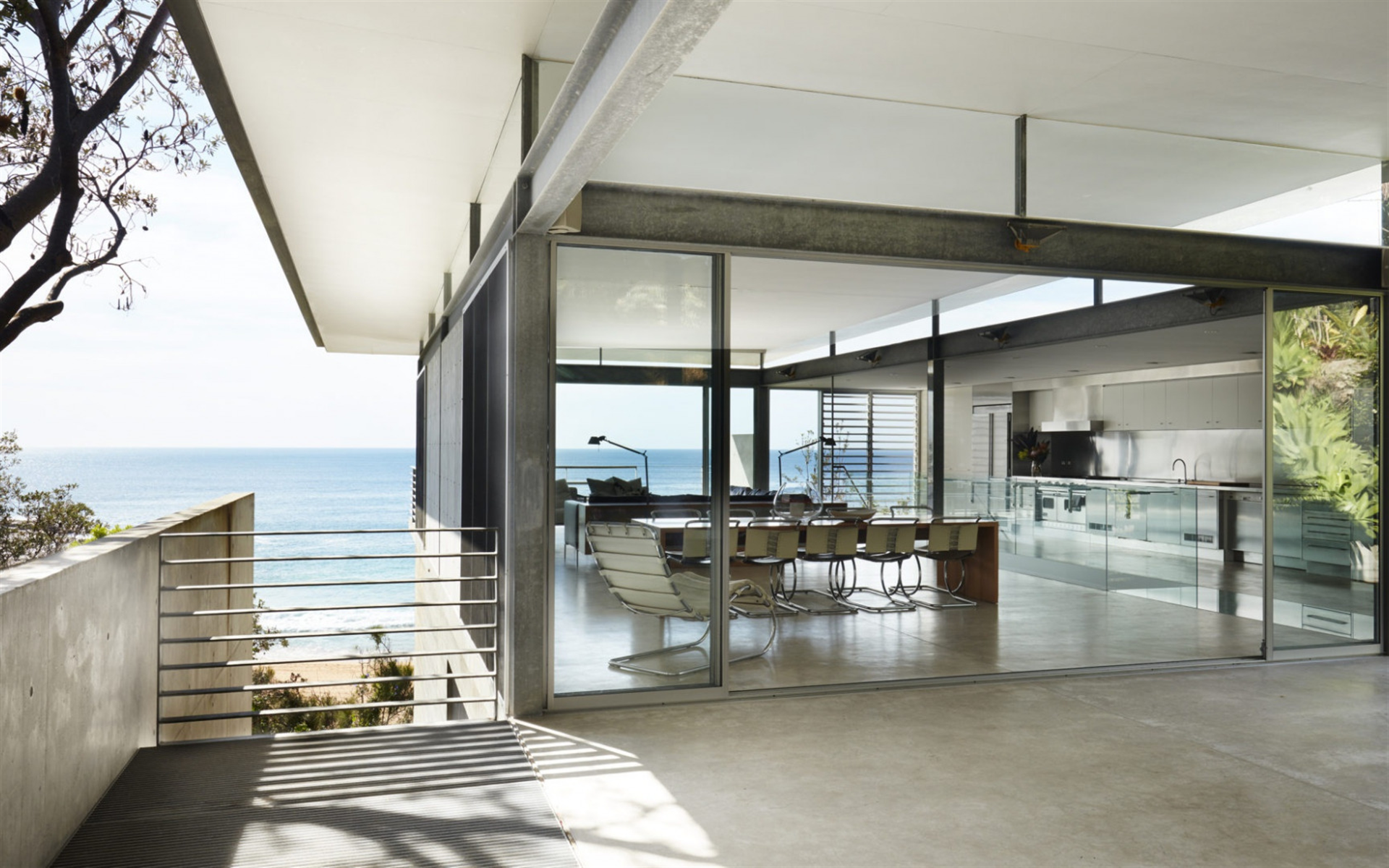 réhabilitation d'architecte d'un salon de maison d'architecte à ossature acier avec vue mer donnant sur un salon avec sol en béton ciré